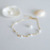 Gold bracelet with pearls on a light gray background