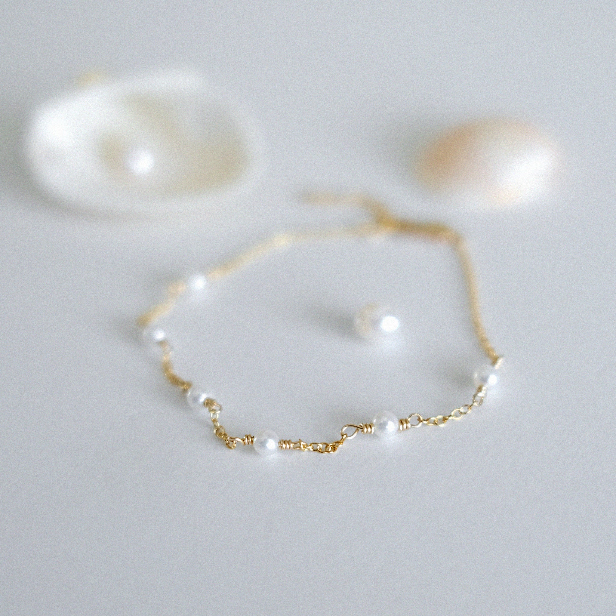 Gold bracelet with pearls on a light gray background