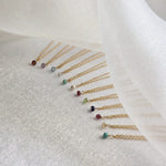 Set of gold necklaces with small gemstones on a white fabric background