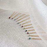 Set of gold necklaces with small gemstones on a white fabric background