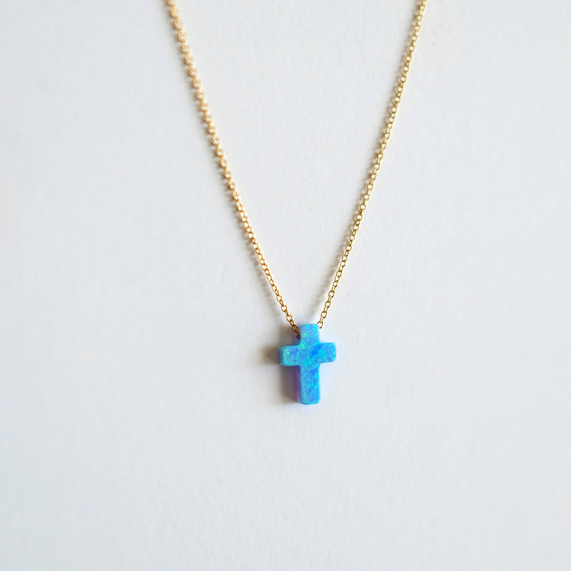 Necklace with a blue cross pendant on a light gray background