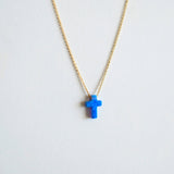 Necklace with a blue opal cross pendant on a light gray background