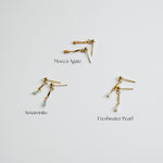 Three gold earrings with gemstones labeled 'Moecca Agate', 'Amazonite', and 'Freshwater Pearl' on a light gray background.