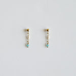 Pair of gold earrings with small beads on a light gray background