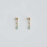 Pair of gold earrings with small beads on a light gray background