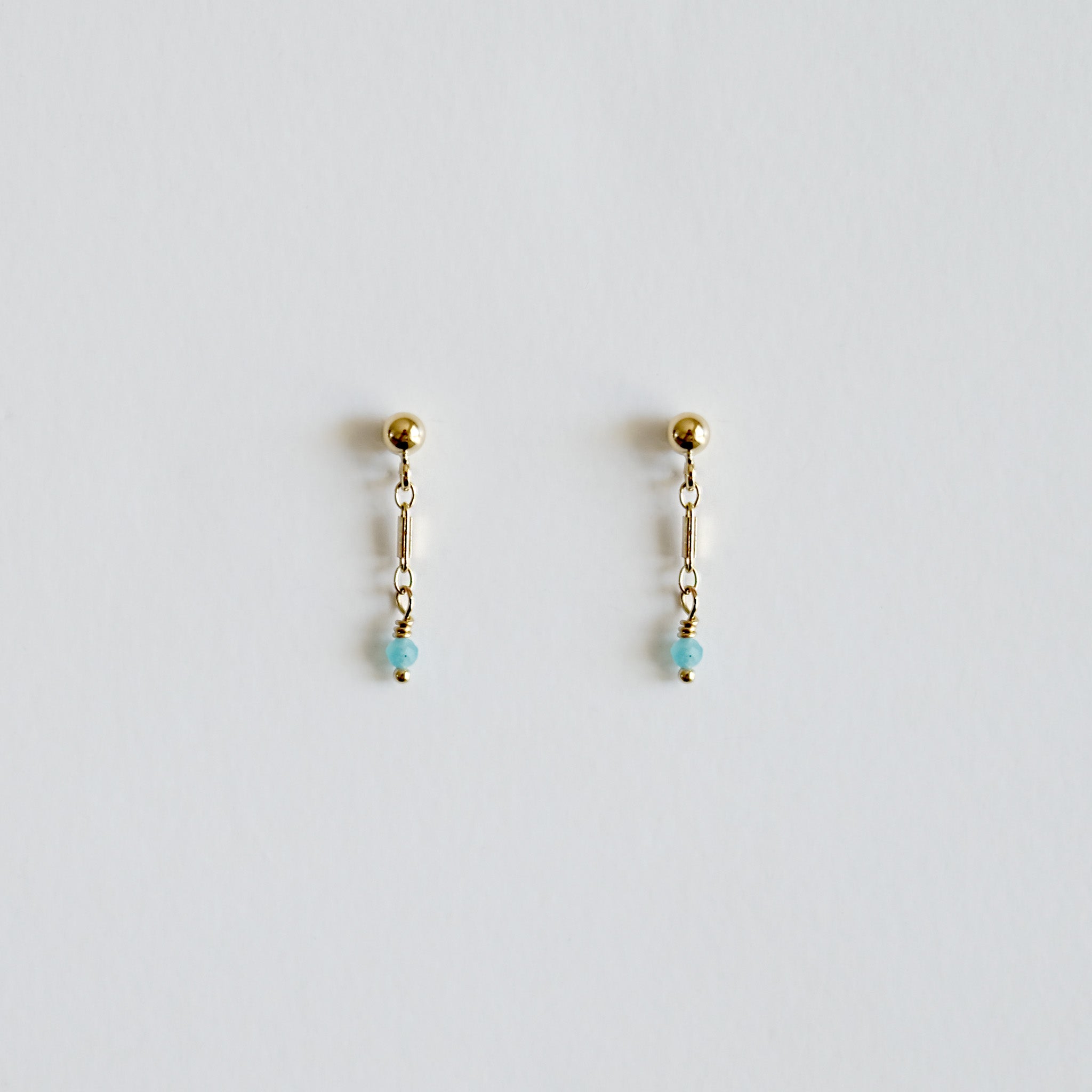 Pair of gold earrings with small beads on a light gray background