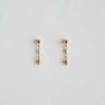 Pair of gold earrings with small beads on a light gray background