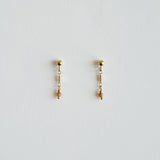 Pair of gold earrings with small beads on a light gray background