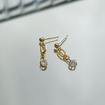 Gold earrings with gemstones on a light gray background