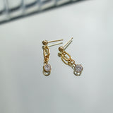 Gold earrings with gemstones on a light gray background