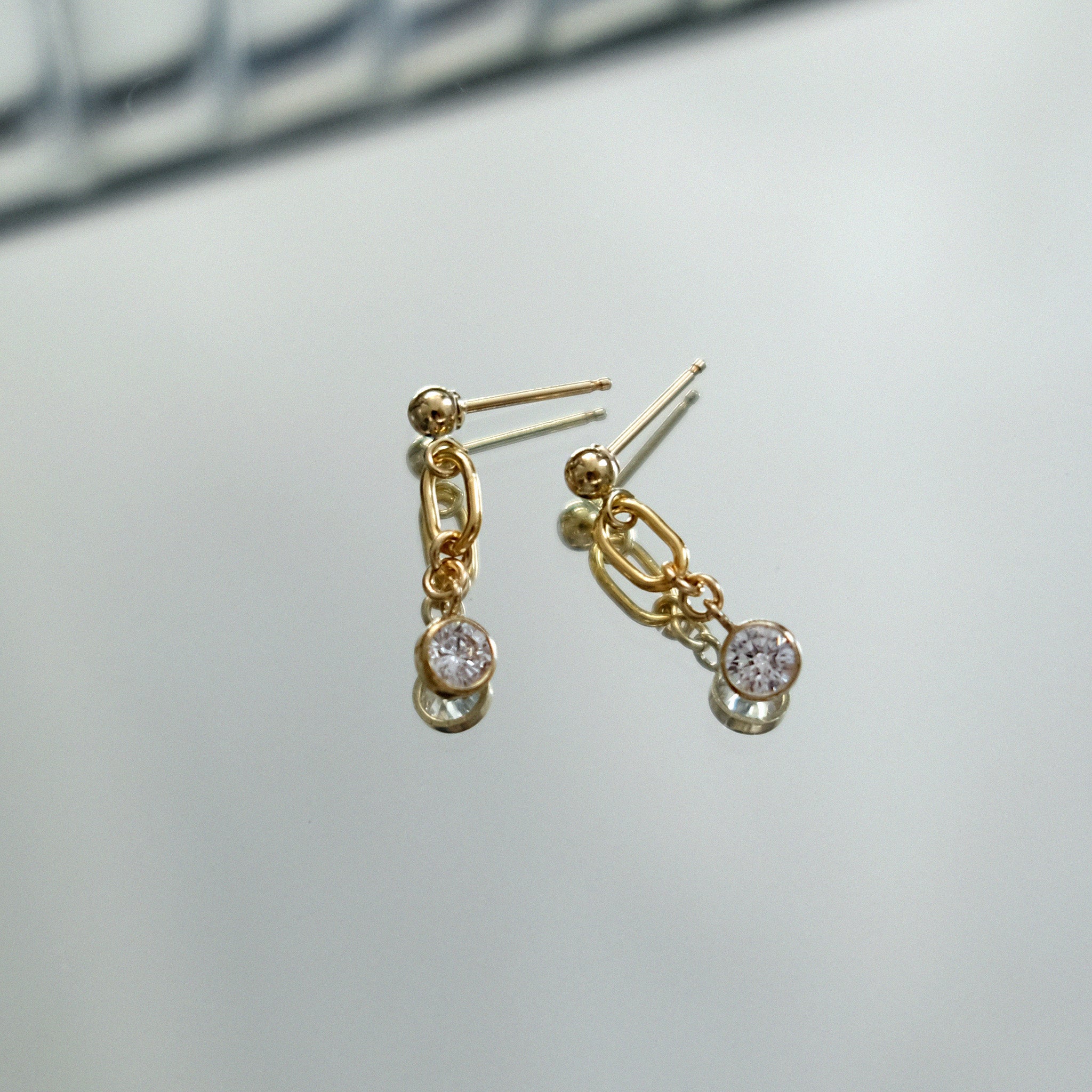 Gold earrings with gemstones on a light gray background