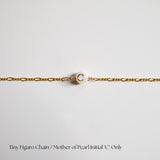 Gold chain with a pearl initial 'C' on a light gray background