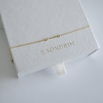 Dainty chain with small bar bracelet on a white box with 'LAONDRIM' branding