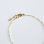 Gold bracelet on a light gray background