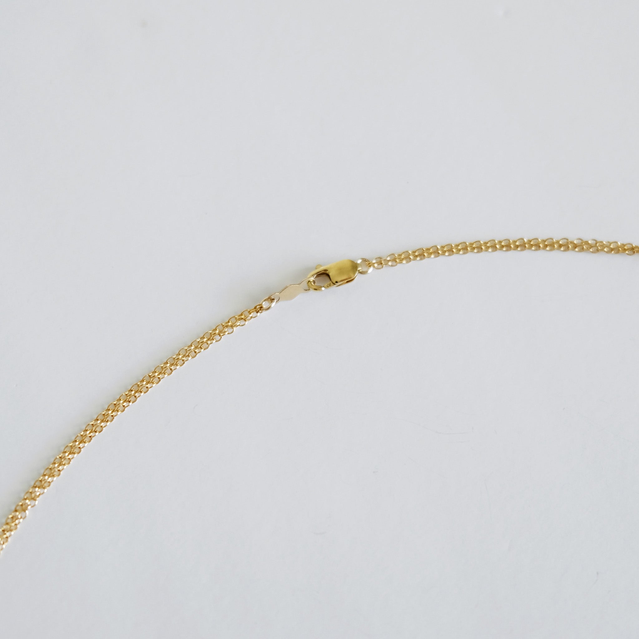 Gold chain necklace on a light gray background