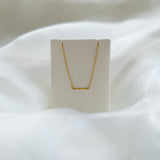 Gold necklace on a white stand with a soft white background