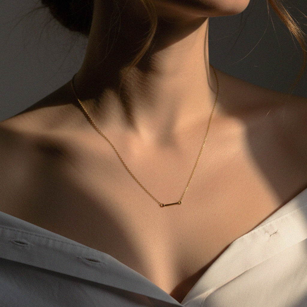 Gold necklace on a person with a neutral background