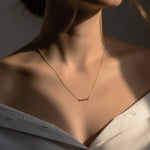 Gold necklace on a person with a neutral background