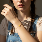 Woman wearing a bracelet with a daisy flower charm, wearing a denim clothing.