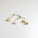 Gold earrings with clear gemstones on a light gray background