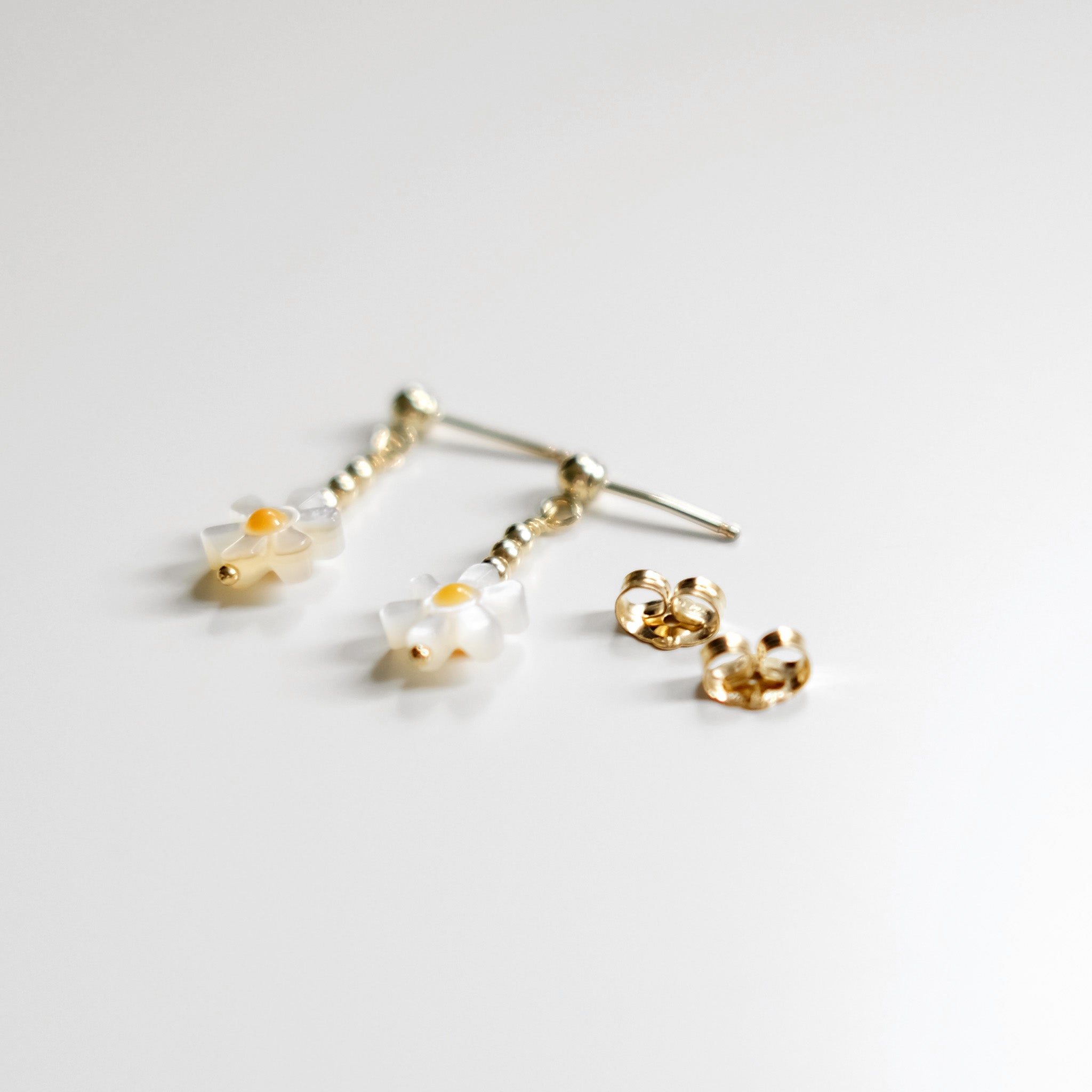 Gold earrings with clear gemstones on a light gray background