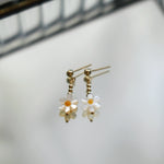 Flower-shaped earrings with gold accents on a light background