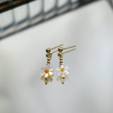 Flower-shaped earrings with gold accents on a light background