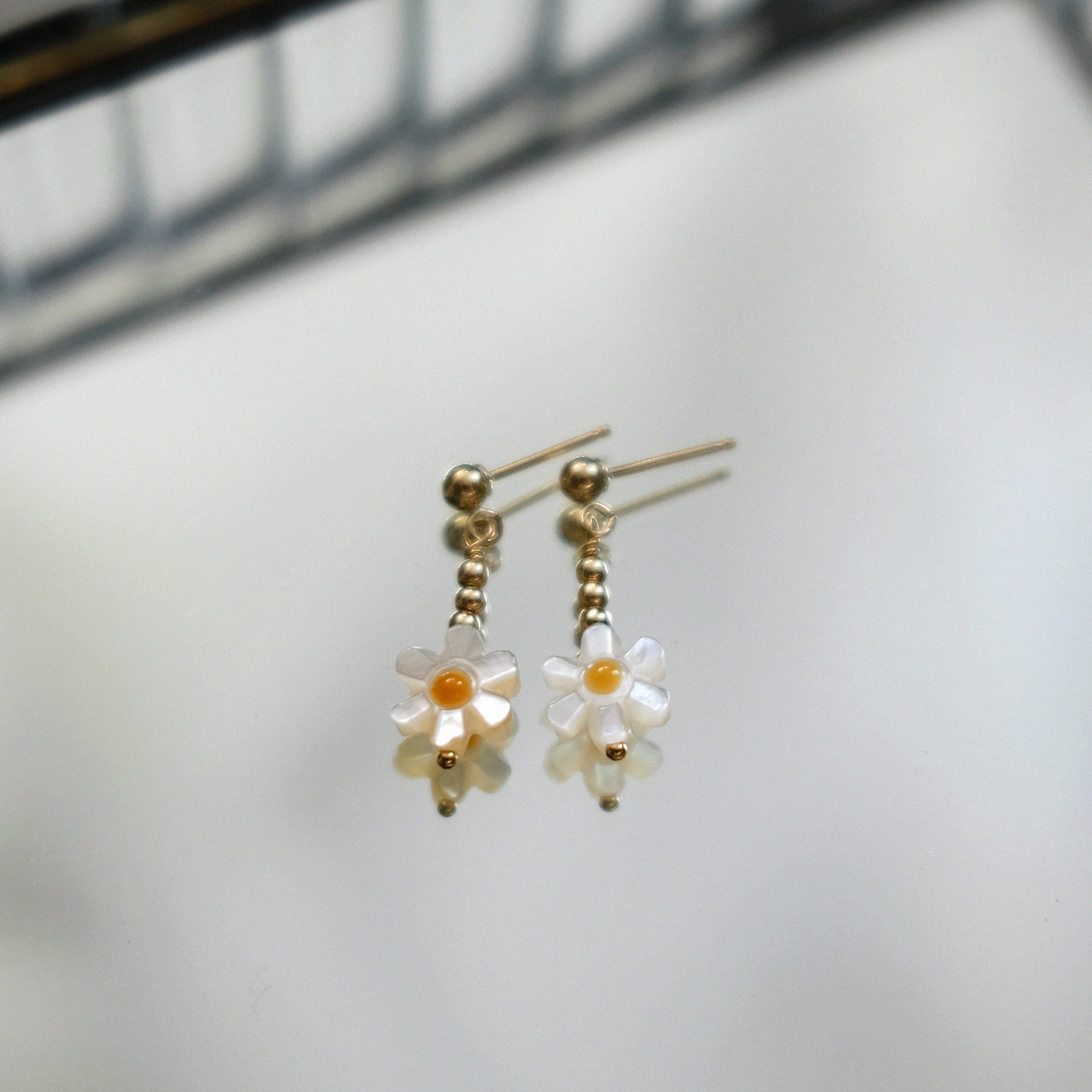 Flower-shaped earrings with gold accents on a light background