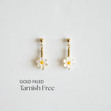 Gold-filled daisy-shaped earrings on a light gray background