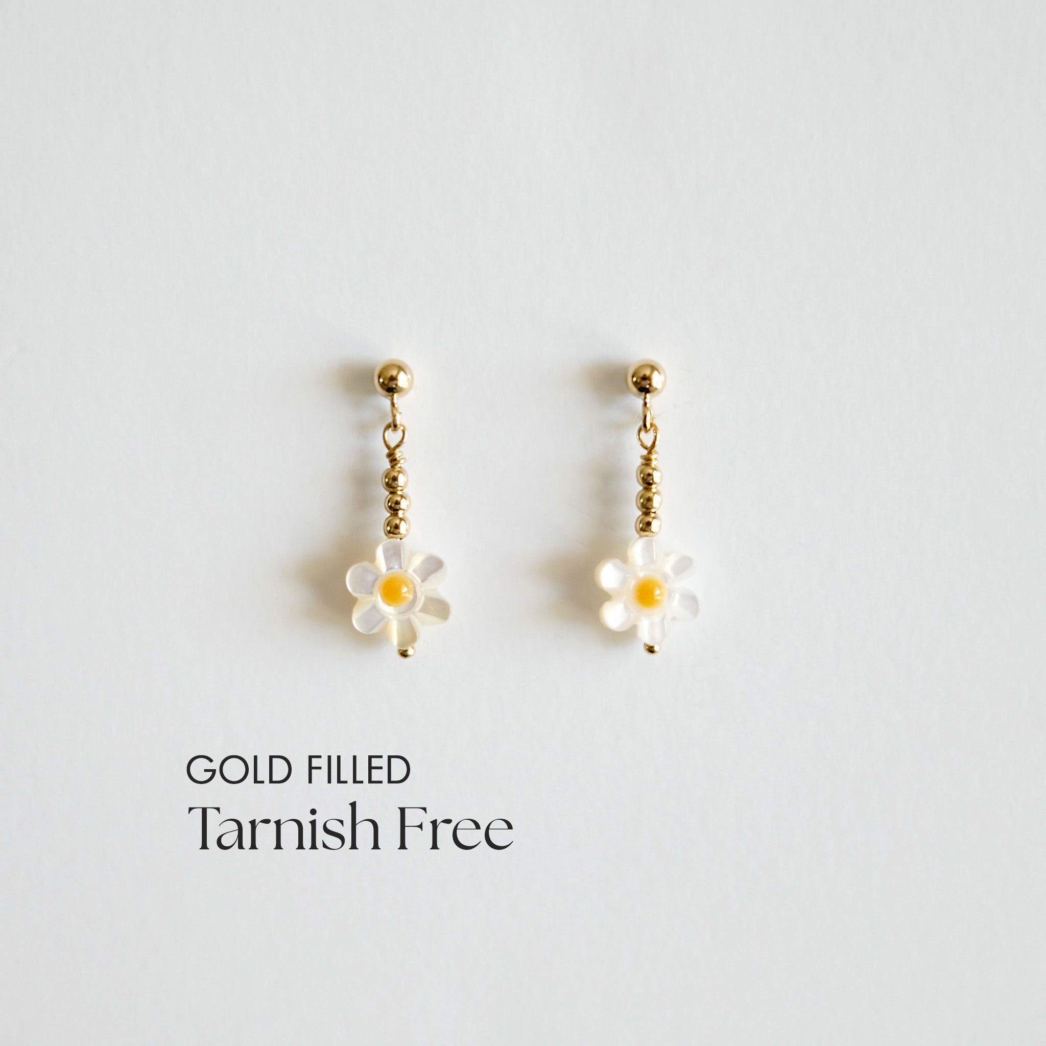 Gold-filled daisy-shaped earrings on a light gray background