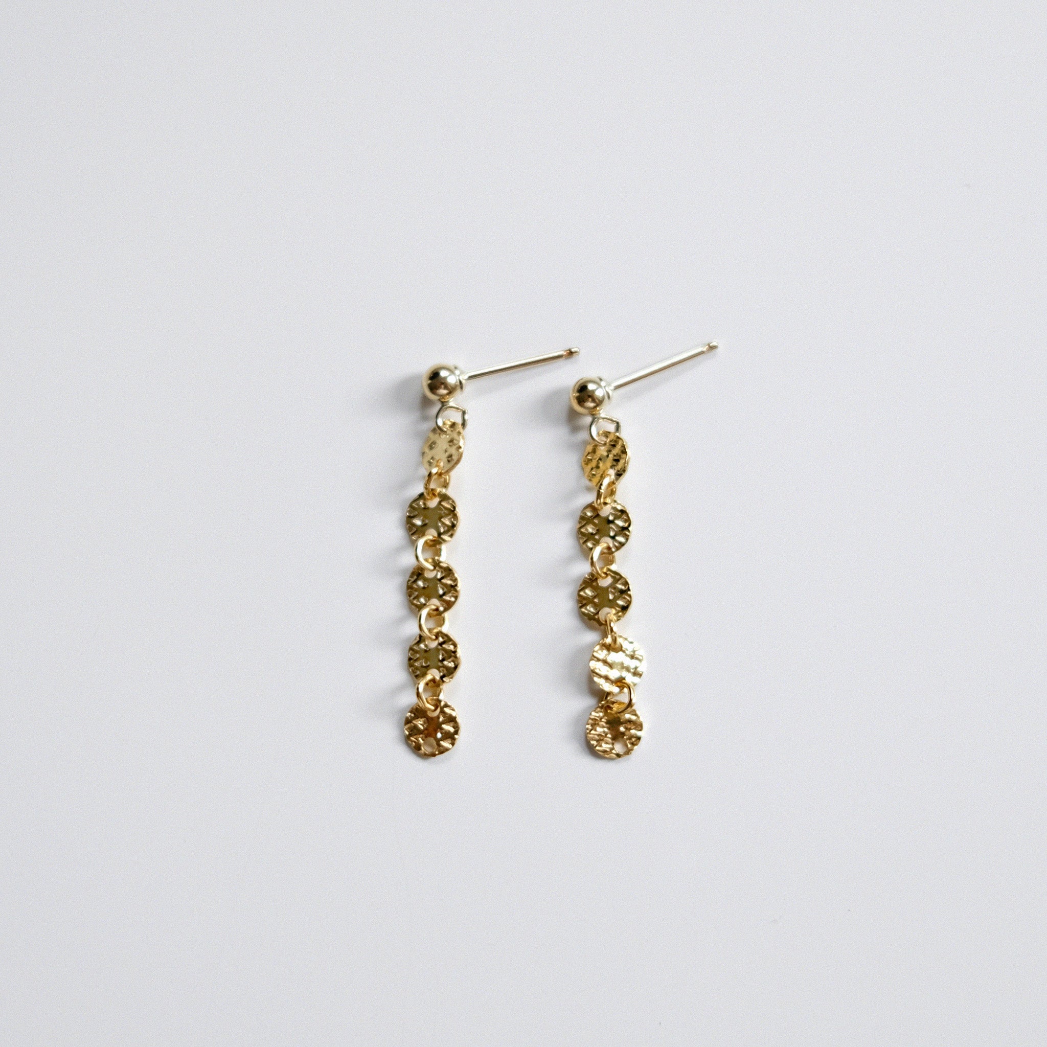 Gold chain earrings on a light gray background
