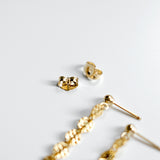 Gold earrings on a light gray background