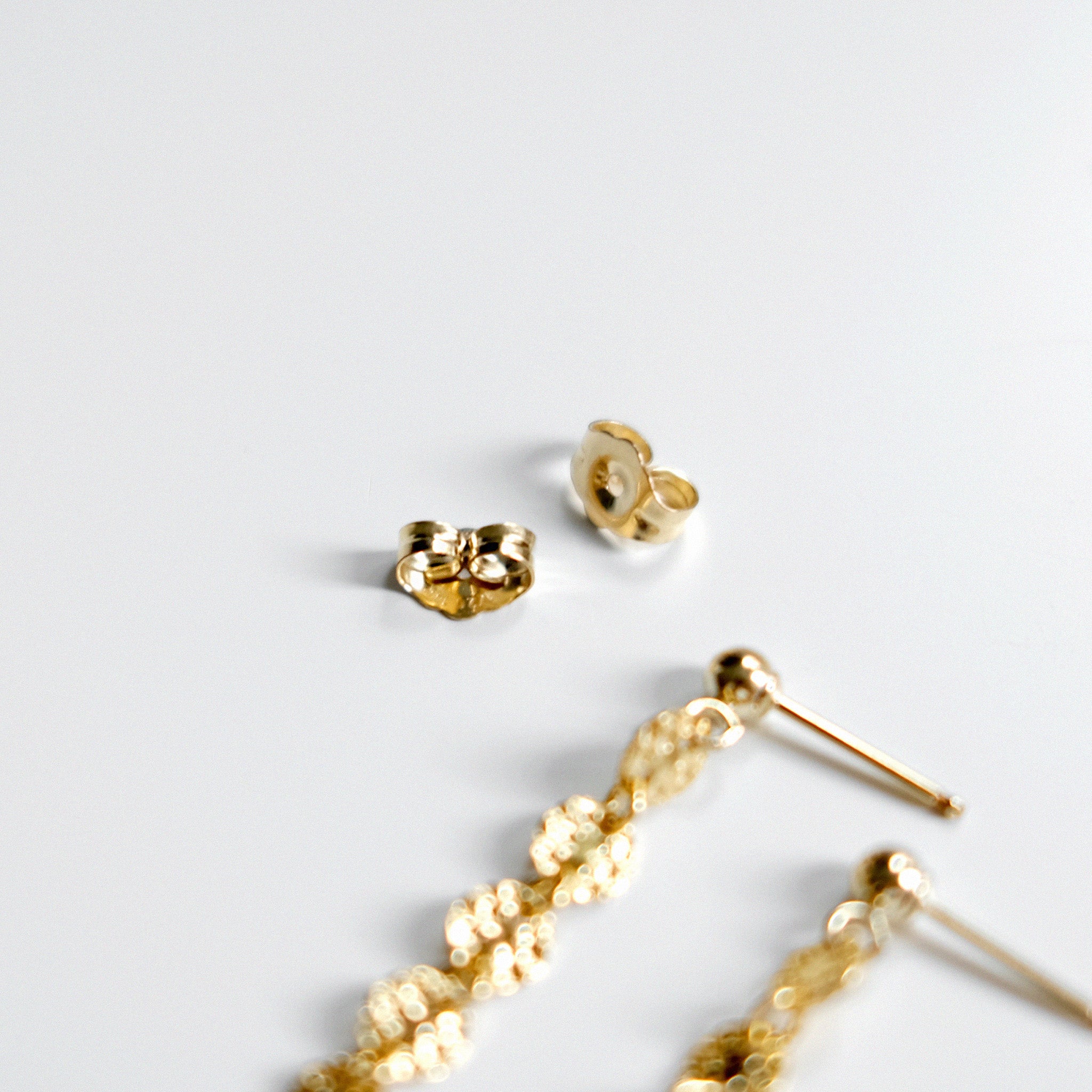Gold earrings on a light gray background