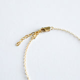 Gold bracelet with clasp on a light gray background