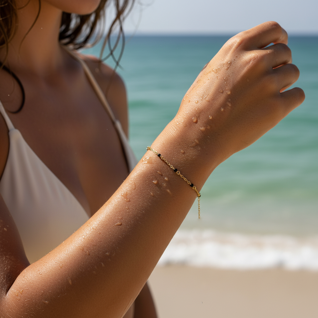 Woman's arm with a gold bracelet on a beach