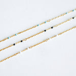 Gold chain bracelet with small beads on a white background