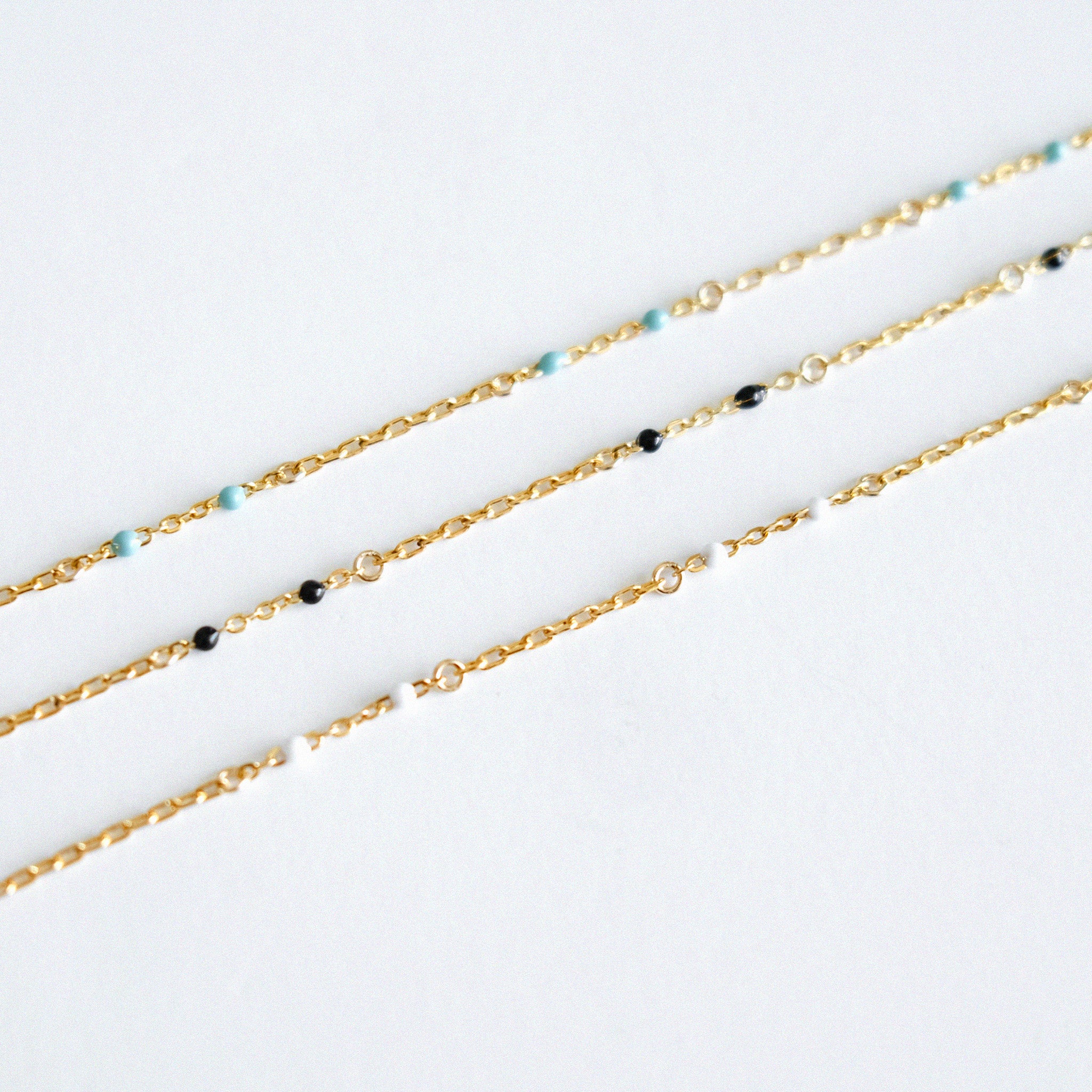 Gold chain bracelet with small beads on a white background