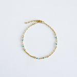 Gold bracelet with mint colour enamel accent on a light gray background
