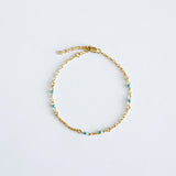 Gold bracelet with mint colour enamel accent on a light gray background