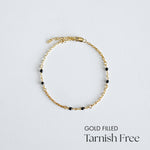 Gold filled bracelet with black beads on a light gray background