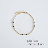 Gold filled bracelet with black beads on a light gray background