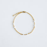 Gold chain bracelet on a light gray background