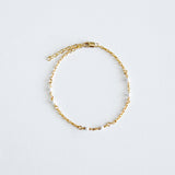 Gold chain bracelet on a light gray background