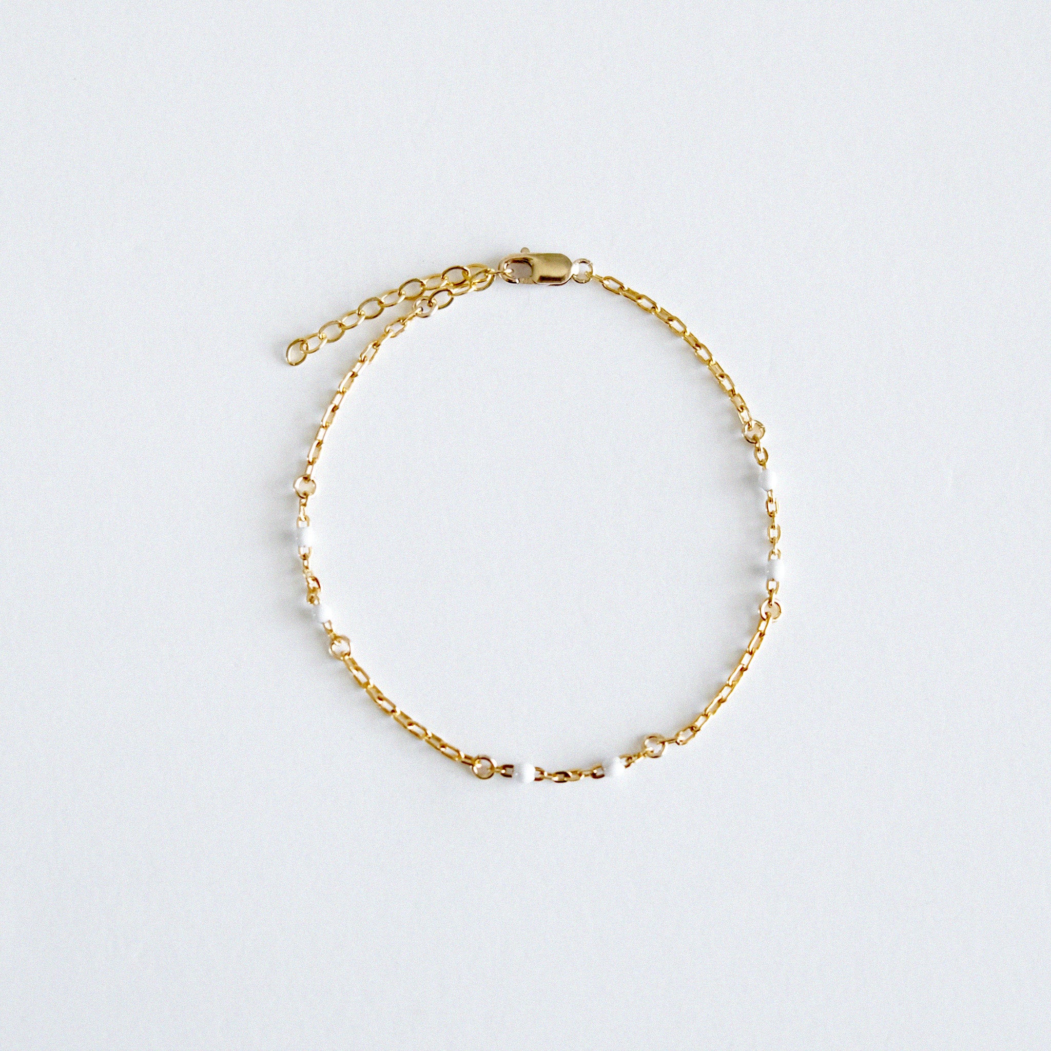 Gold chain bracelet on a light gray background