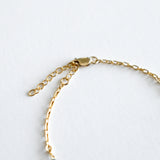 Gold chain bracelet on a light gray background