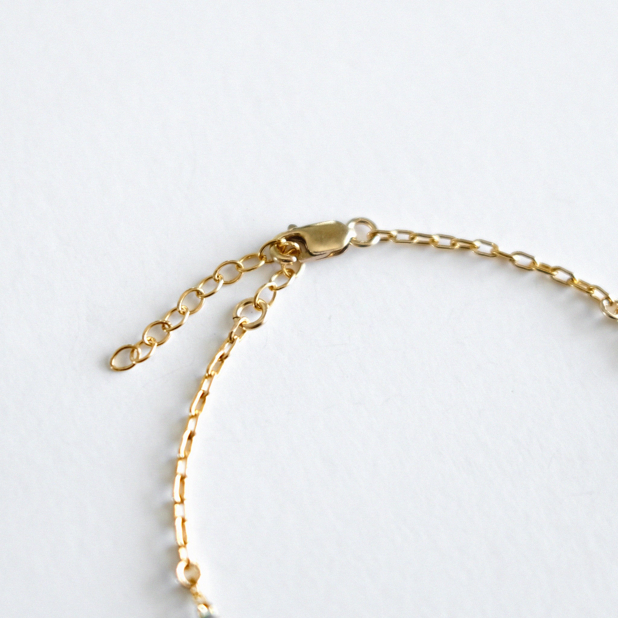 Gold chain bracelet on a light gray background
