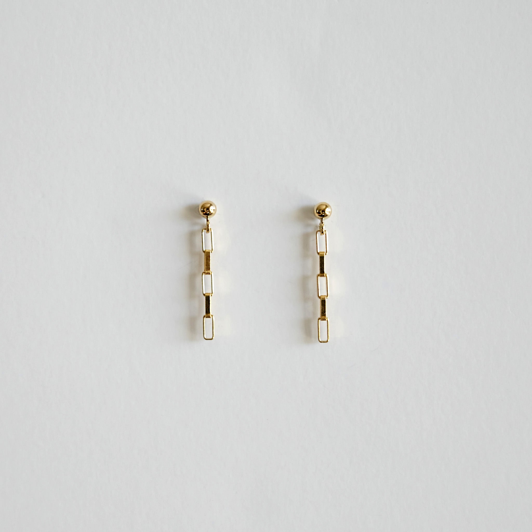 Pair of gold earrings on a light gray background