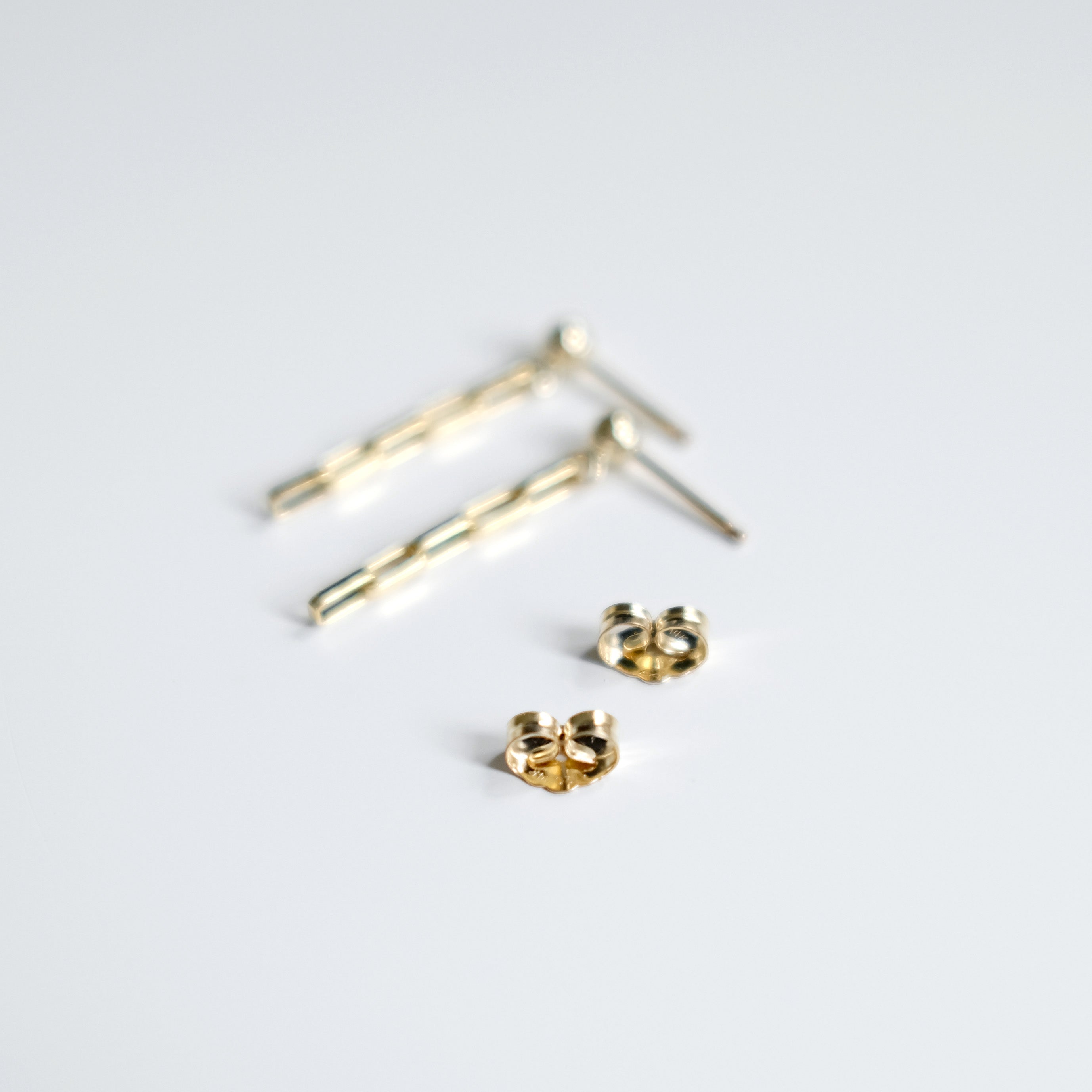 Gold stud earrings on a light gray background