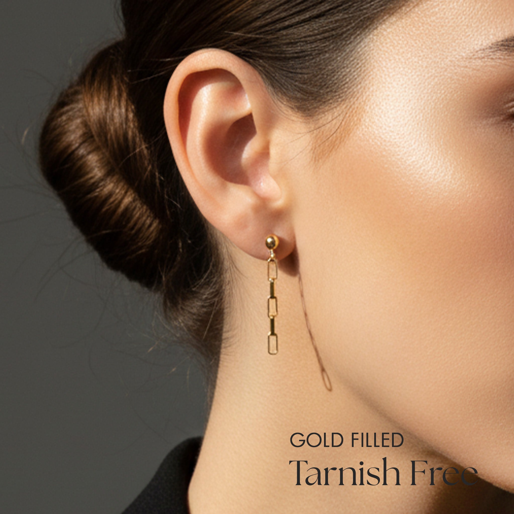 Gold filled earring worn by a person with a neutral background