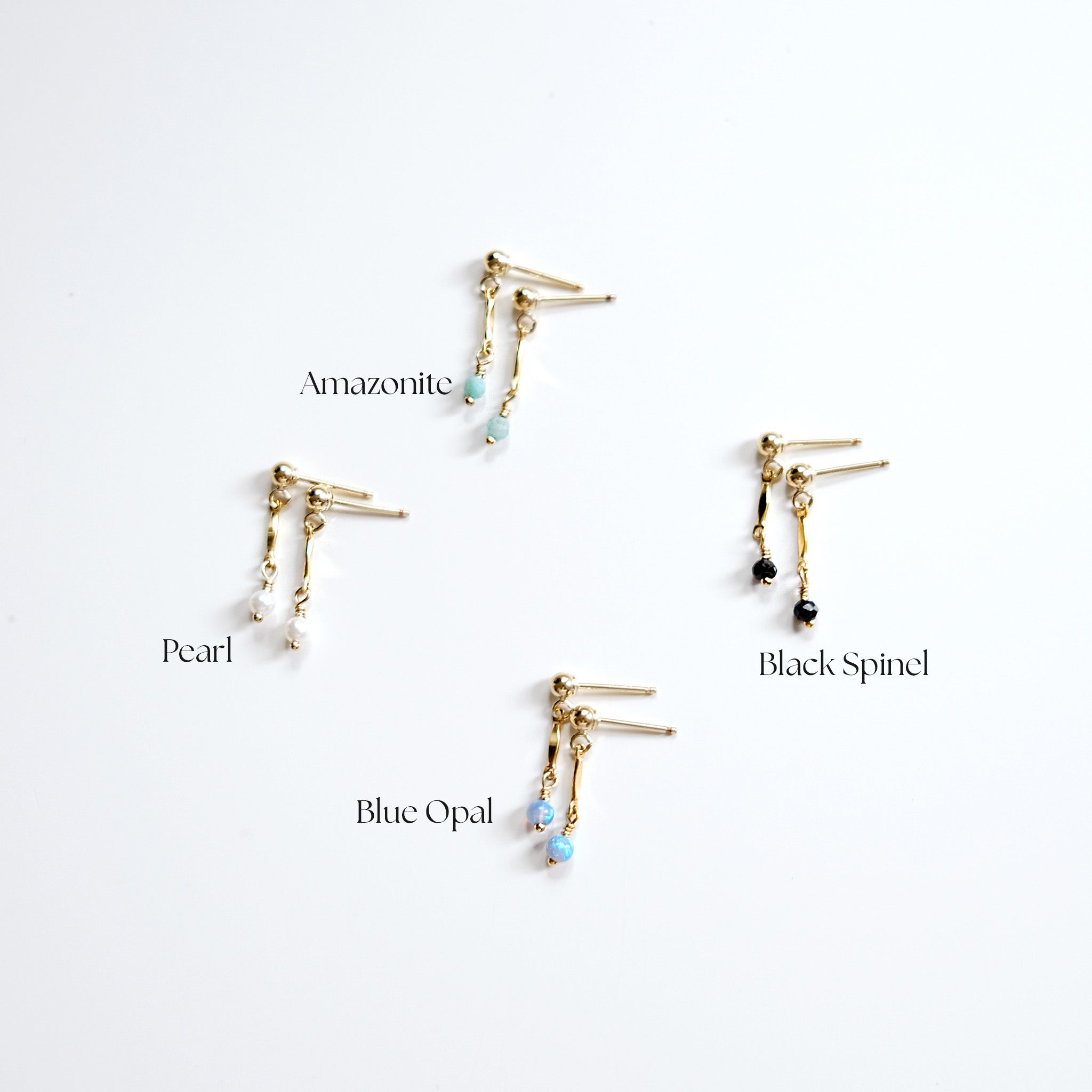 Four pairs of gold earrings with different gemstones on a white background